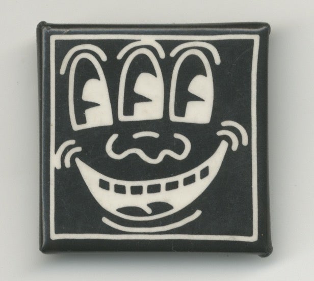 Item #6362 White on Black Three-Eyed Smiley Face Pin. Keith Haring.